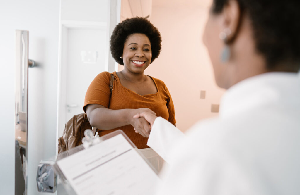 A smiling woman shakes a doctor's hand